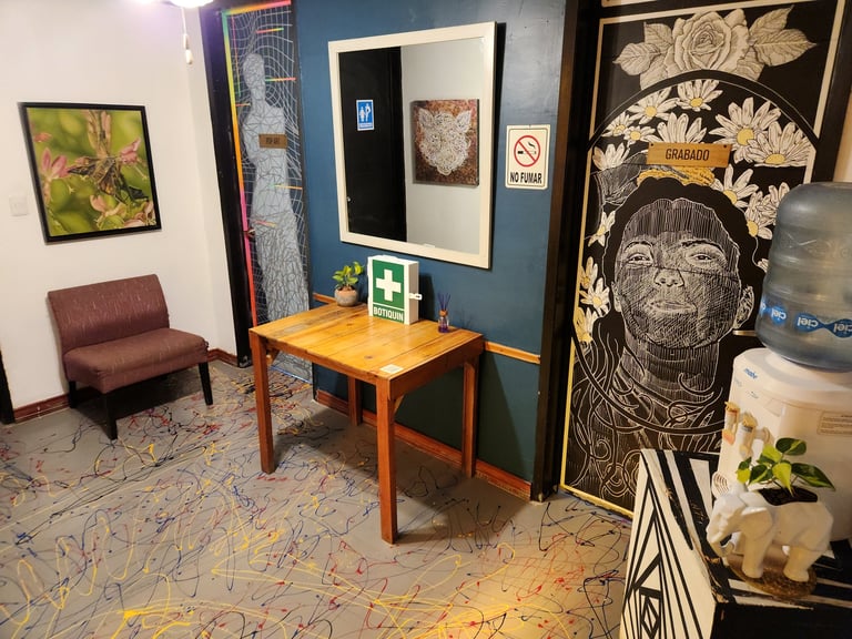 Modern office or waiting room with burgundy chair, wooden desk, artwork on walls, and decorative botanical prints on dark wall.