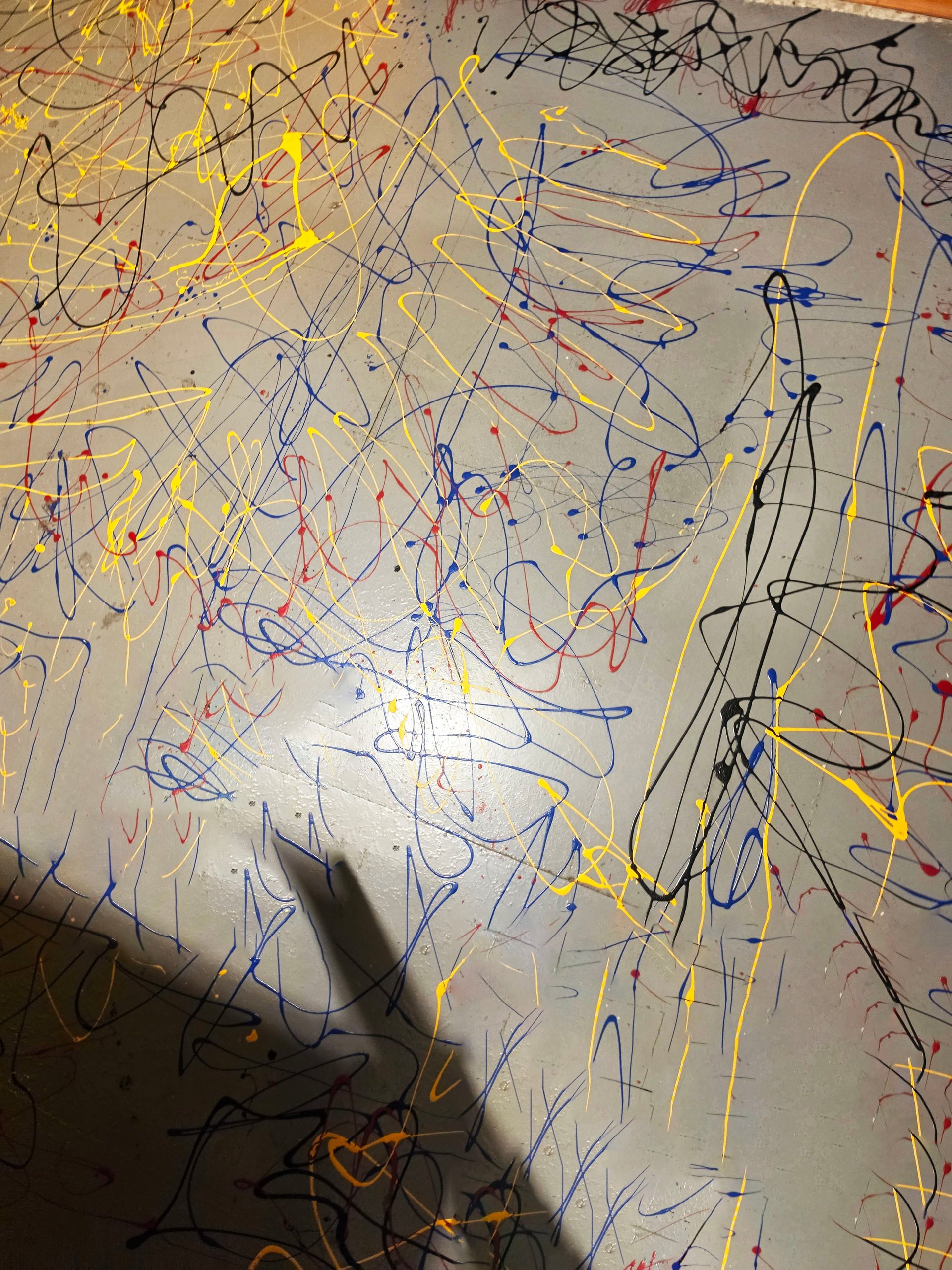 Childs abstract crayon drawing with colorful scribbles and lines in yellow, blue, red, and black on white paper