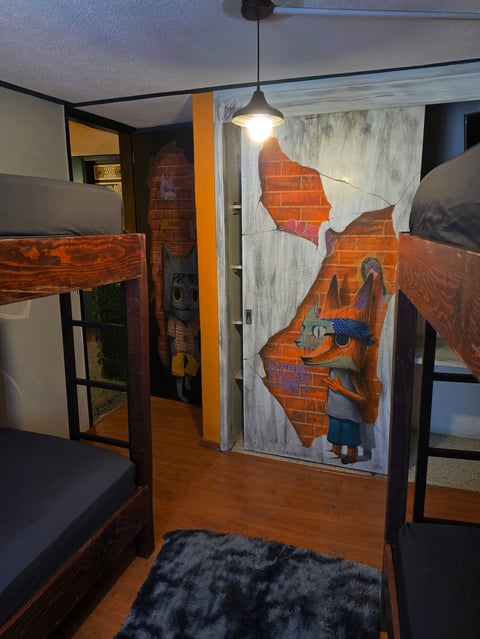 Modern loft bedroom with wooden bunk beds, pendant light, and street art mural on exposed brick wall